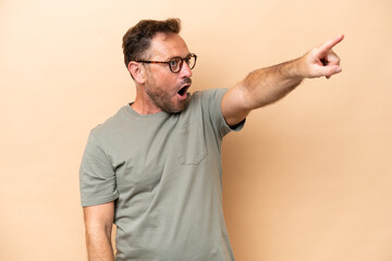 Middle age caucasian man isolated on beige background pointing away