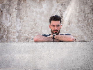 Photo of a confident man leaning against a wall with his arms crossed