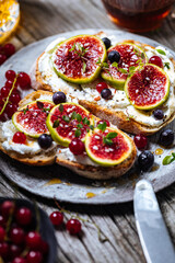 Toast spread with cream cheese, figs, currants and honey. Tasty and healthy brunch. Colourful scene.