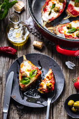 Healthy pizza with eggplant or aubergine with tomato sauce, mozzarella cheese and basil leaves. Placed on rustic wooden board with ingredients
