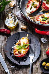 Healthy pizza with eggplant or aubergine with tomato sauce, mozzarella cheese and basil leaves. Placed on rustic wooden board with ingredients