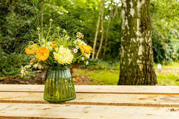 bouquet of yellow flowers in a vase on a wooden table