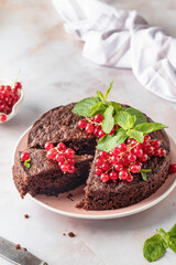 Cutted Tasty homemade chocolate cake brownie decorated with red currant berries and mint on white marble table