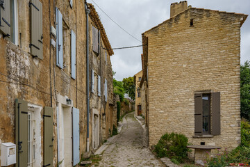 A beautiful narrow street between old country houses built of decaying bricks and stones.