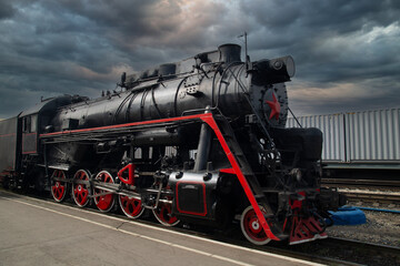 An old steam locomotive of the early 20th century on the railway track.