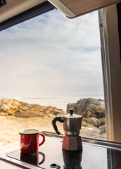 Blick aus dem Wohnmobil auf das Meer, Camping Kocher im Vordergrund