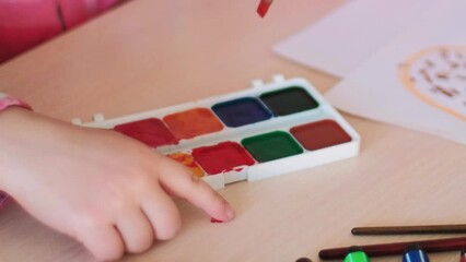 Child creative hobby. Painting learning. Little girl enjoying art activity with watercolor and paintbrush at table at talent development school.