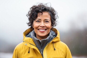 Medium shot portrait of an Indian woman in her 50s wearing a warm parka against a white background