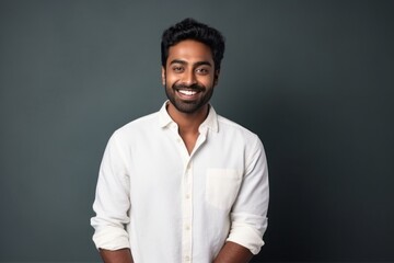 Medium shot portrait of an Indian man in his 20s in a minimalist background