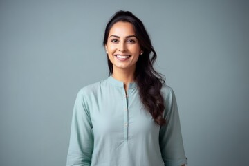 Medium shot portrait of an Indian woman in her 30s wearing salwar kameez in a minimalist background