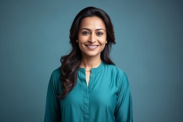 Medium shot portrait of an Indian woman in her 30s wearing salwar kameez in a minimalist background