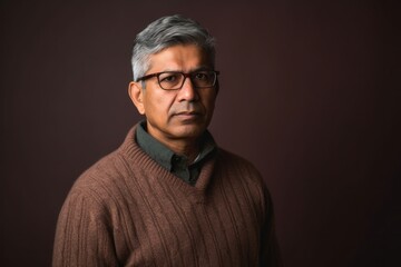 Fototapeta premium Lifestyle portrait of an Indian man in his 50s in a minimalist background
