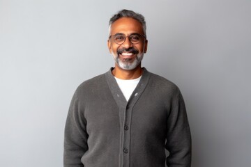 Medium shot portrait of an Indian man in his 50s in a minimalist background
