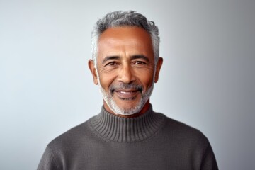 Medium shot portrait of an Indian man in his 70s in a minimalist background