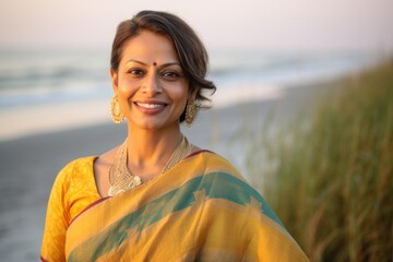 Beautiful indian woman in saree on the beach at sunset