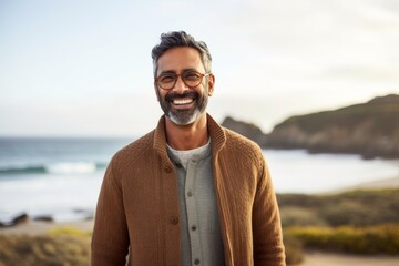 Portrait of smiling mature man with eyeglasses standing on beach