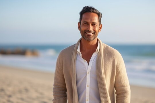 Portrait of a handsome young man smiling at the camera on the beach