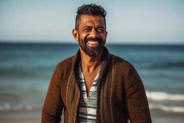 Handsome young Indian man smiling at camera on the beach.