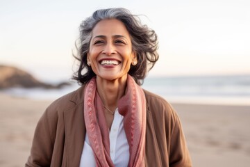 Portrait of smiling mature woman walking on beach at sunset in autumn