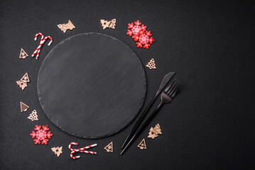 Empty dark ceramic plate with elements of Christmas decorations