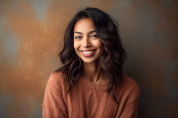 Fototapeta premium Portrait of a beautiful smiling young woman in sweater on brown background