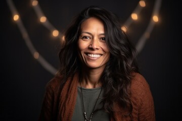 Fototapeta premium Portrait of a beautiful woman smiling at the camera with lights in the background