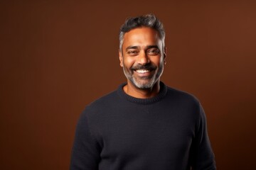 Medium shot portrait of an Indian man in his 40s in an abstract background