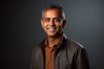 Fototapeta premium Portrait of a smiling Indian man in a leather jacket on a dark background