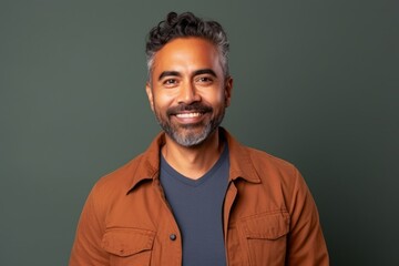 Obraz premium Portrait of a handsome Indian man smiling at the camera against a green background