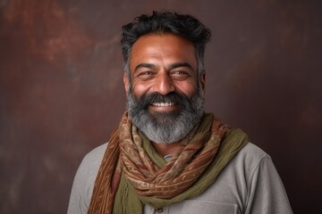 Portrait of a smiling bearded Indian man wearing a scarf and looking at the camera.