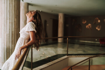 Chica joven en hall de hotel en la escalera de caracol posando y andando