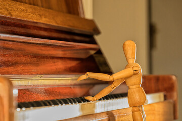 Wooden mannequin playing console piano.