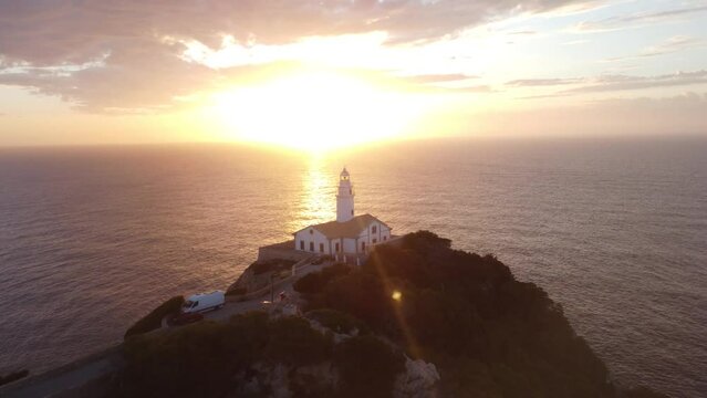 Drone view over Far de Capdepera lighthouse in Spain with golden sunset sky