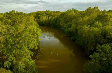 Aerial shot of two boats sailing in Haw River surrounded by lush greenery, North Carolina.
