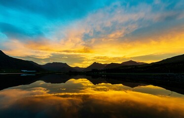 Picturesque lake with the sun rising over a mountain range in the background