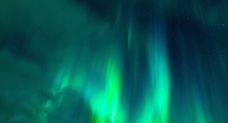Beautiful night sky filled with an array of vibrant green northern lights or aurora borealis