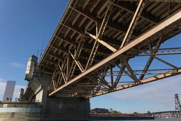 Sturdy, steel bridge next to a calm body of water, with a crisp blue sky in the background