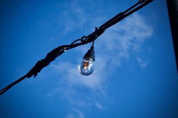 Low-angle shot of a lamp depented on the line under the dark blue sky.
