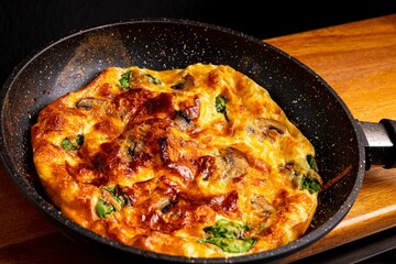 Freshly-fried pan pizza topped with cheese and mushrooms on a wooden board