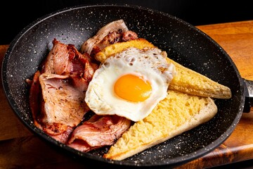 Breakfast plate featuring a freshly fried egg, a slice of bread, and bacon slices