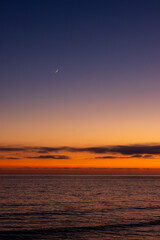 Fototapeta premium The moon above ocean during sunset