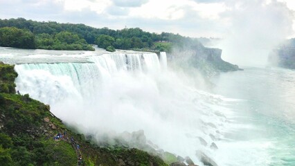 Majestic view of Niagara Falls with people enjoying it by walking along its side