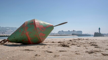 Vintage green and red buoy on a sandy shoreline