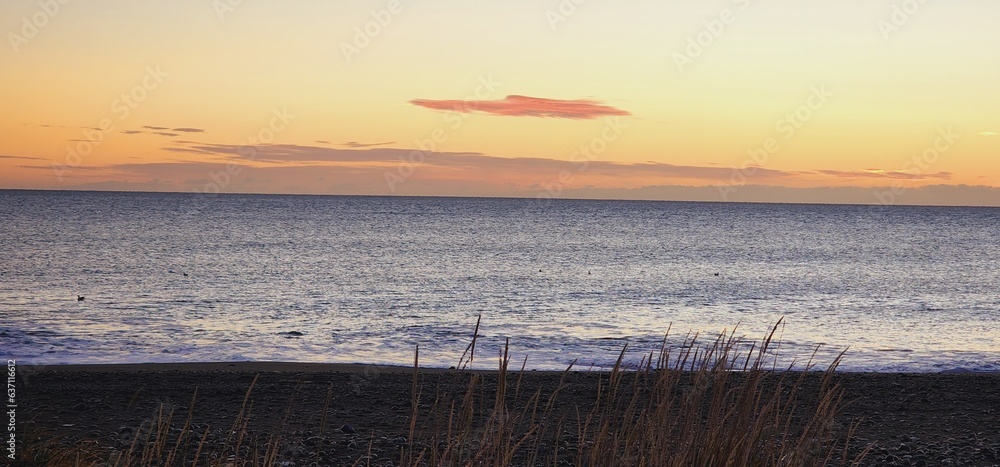 Sticker tranquil body of water against the backdrop of a sky at sunset.