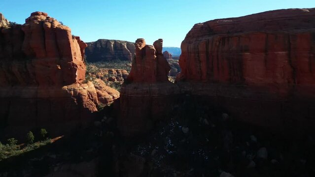Drone view over red cliffs surrounded by green bushes on a sunny day