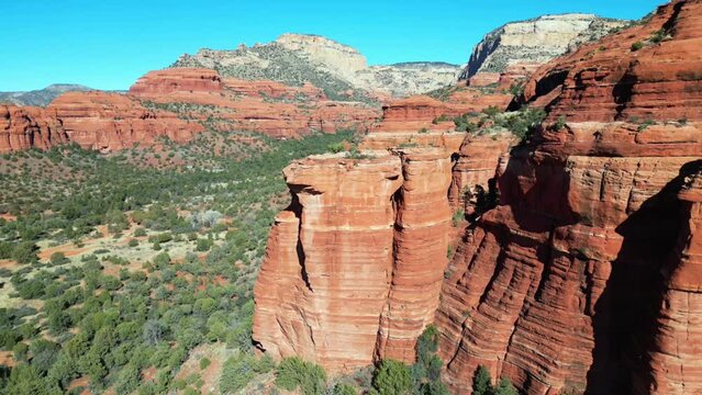 Drone view over red cliffs surrounded by green bushes on a sunny day