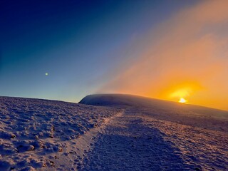 the sun sets over snow covered hills on a cold day