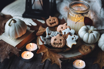 Homemade halloween holiday treats for kids. Gingerbread cookies on wooden board, decorated with pumpkins and autumn leaves. Cozy fall home atmosphere