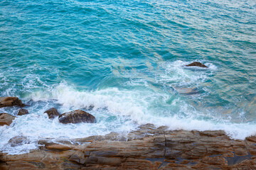 The blue stormy sea beats a wave against the stones. Water surface, seashore, top view.