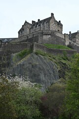 Fototapeta na wymiar Vertical of Edinburgh Castle on top of a green hill on a cloudy day in Scotland